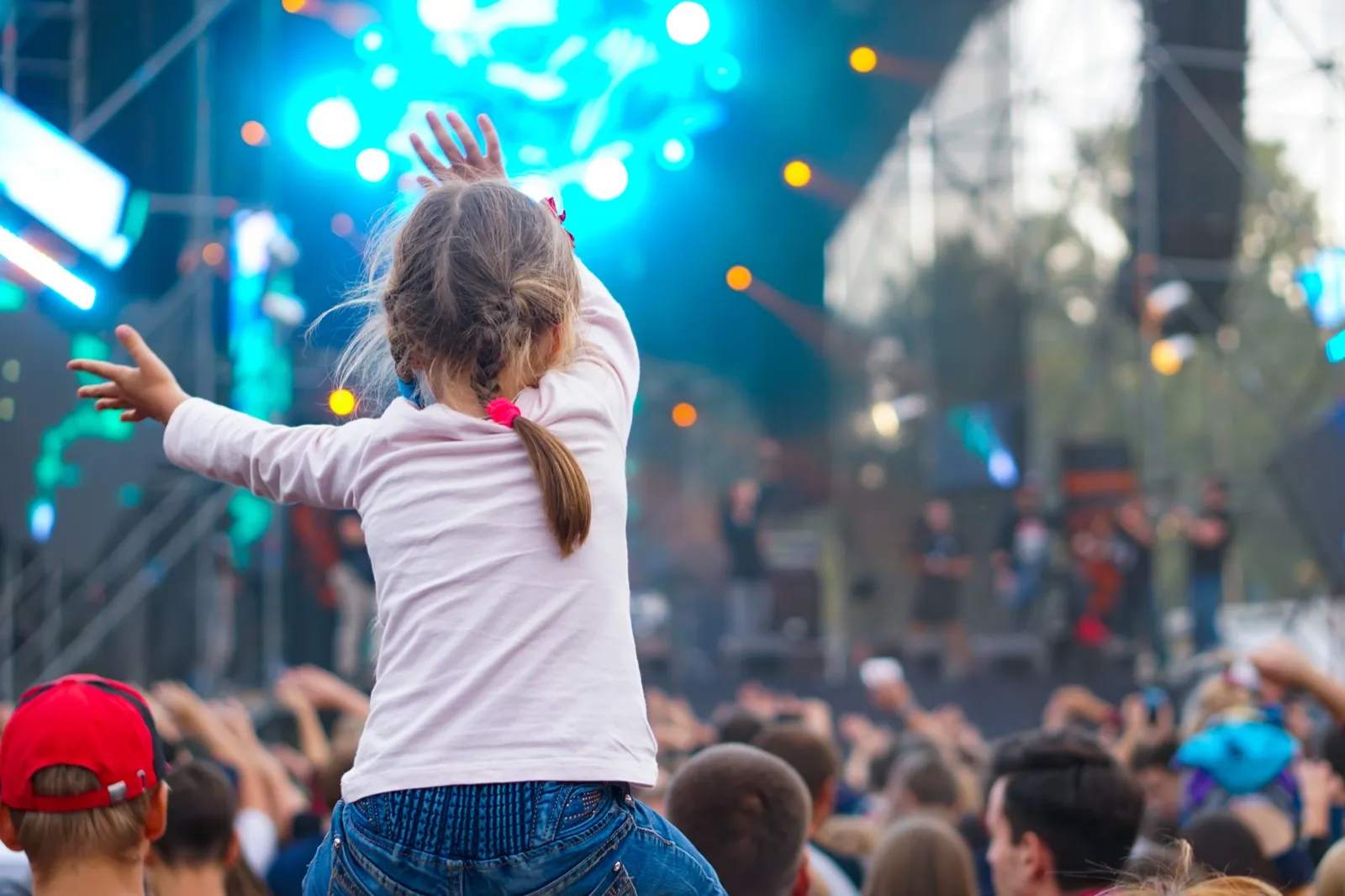Ein Kind erlebt ausgelassen ein Konzert auf den Schultern getragen